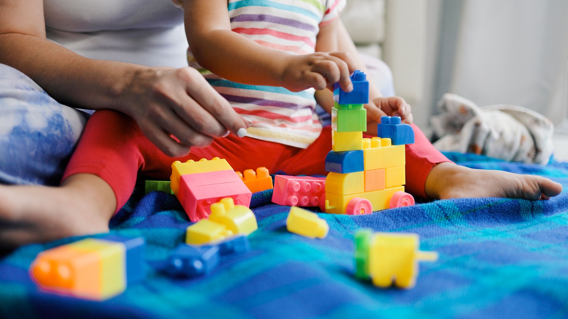 Mother and baby kid playing with block toys together at home. Mom and daughter, family relationship